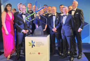 A group of men and women smiling after an award win.